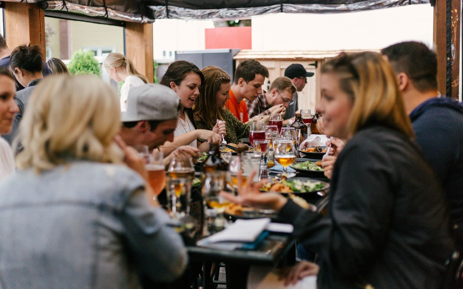 Drukbezet terras met gasten aan lange tafels